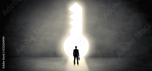 Businessman standing alone in front of a big keyhole
