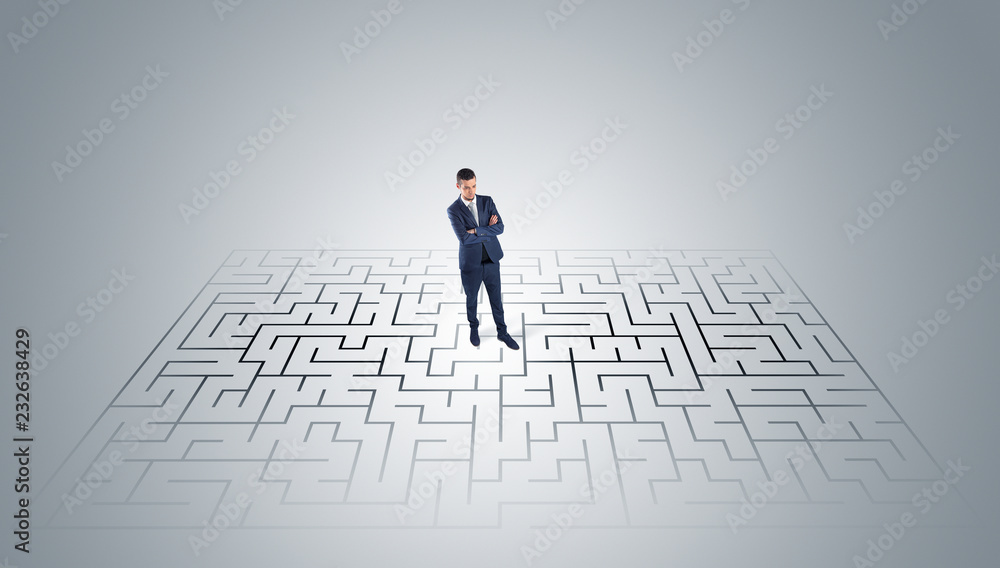 Elegant businessman looking for a solution in a middle of a maze
Elegant businessman looking for a solution in a middle of a maze
