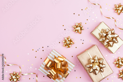 Fashion gifts or presents boxes with golden bows and star confetti on pink pastel background top view. Flat lay composition for birthday, christmas or wedding.