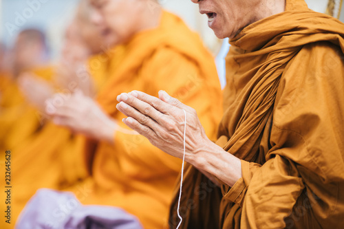 Close up of Thai monk praying focus at hand with white rope.