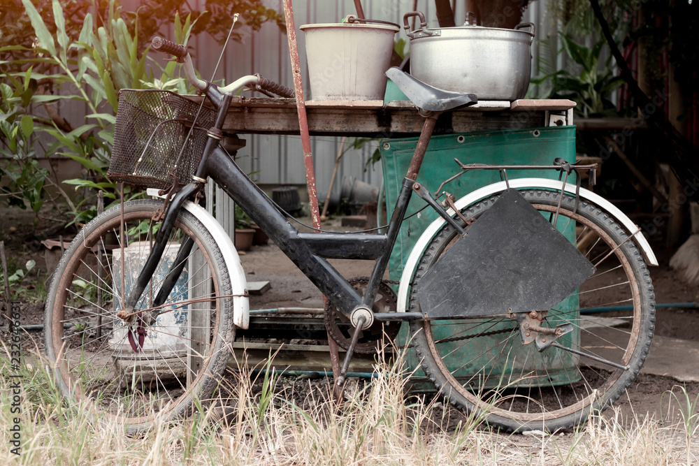 Old Bicycle parked against the wooden table with empty home appliances.