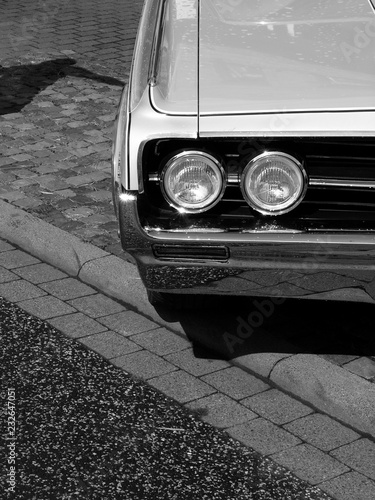 Kühlergrill mit Doppelscheinwerfer eines amerikanischen Coupé der Sechzigerjahre beim Oldtimertreffen Golden Oldies in Wettenberg Krofdorf-Gleiberg bei Gießen in Hessen in neorealistischem Schwarzweiß photo