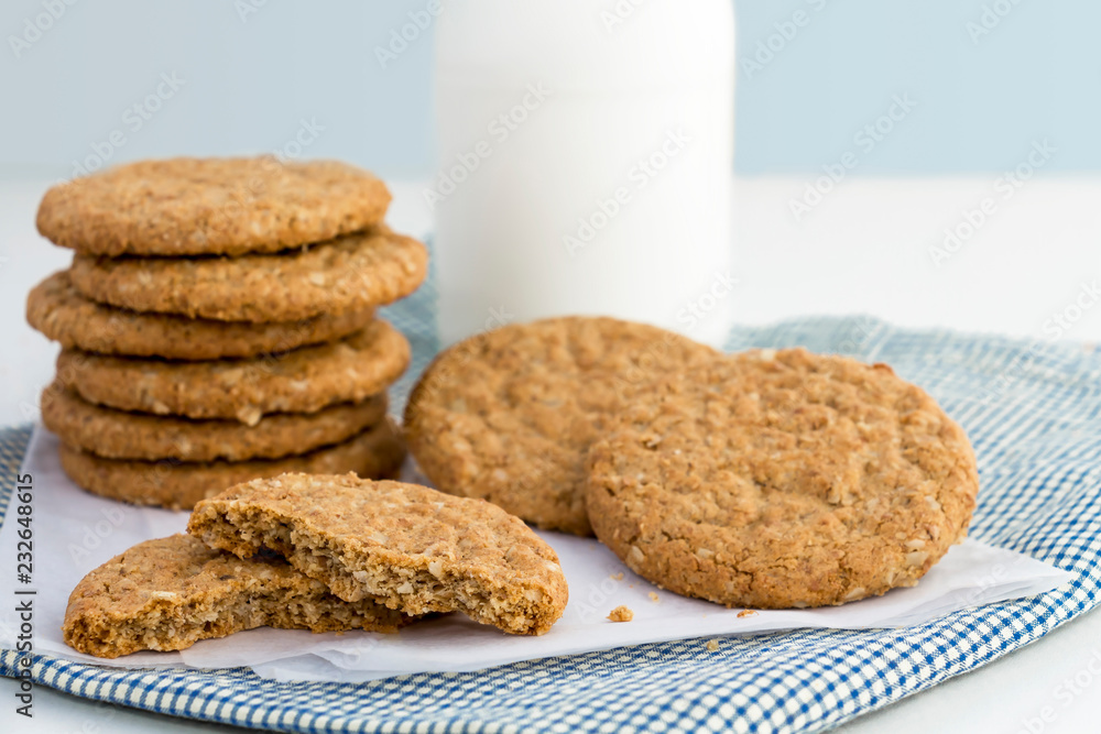 Homemade shortbread cookies made of oatmeal are stacked on cloth with glass bottle of milk on white background. Concept food healthy snack for enjoy in holiday with copy space for text. Homemade shortbread cookies made of oatmeal are stacked on cloth with glass bottle of milk on white background. Concept food healthy snack for enjoy in holiday with copy space for text.