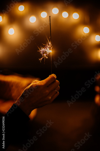 Obraz na płótnie Sparkling Bengal fire in man hand on white background with yellow ballons numbers 2019. Christmas Holiday Concept w salonie
