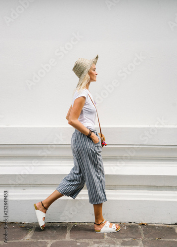 Stylish traveler walking against white wall photo