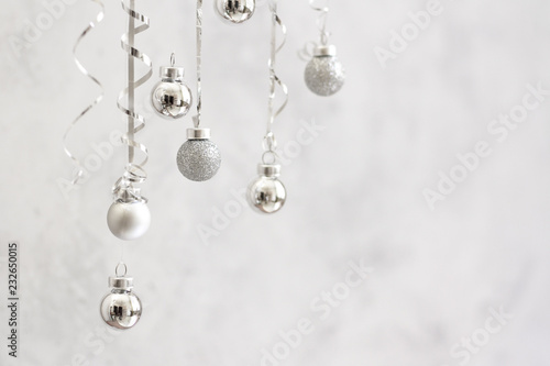 Trendy christmas background. Silver ball Ornaments hanging on gray stone background. minimal christmas concept.