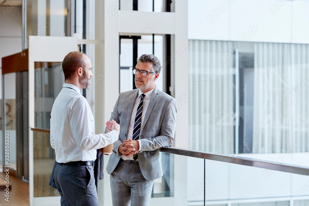 Businessmen Talking While Standing By Railing Businessmen Talking While Standing By Railing