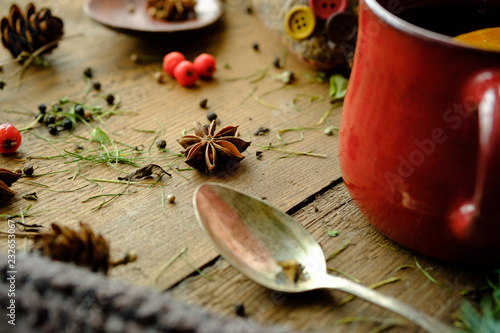 Details of still life in the living room home interior. Beautiful cup of tea with spices and sweaters on a wooden background. Cozy autumn-winter concept.