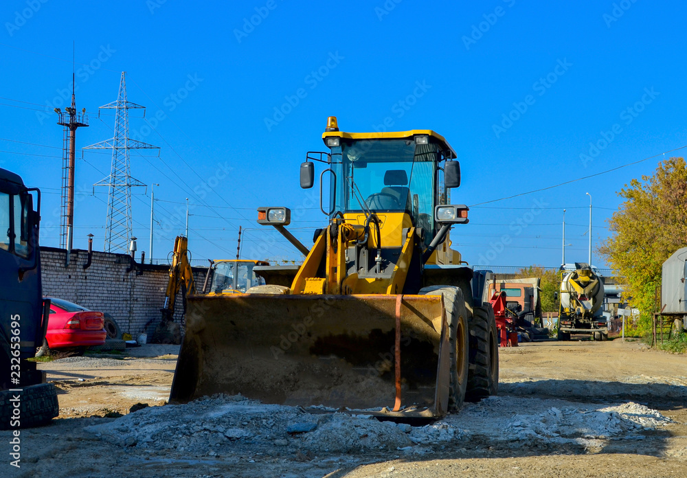 Yellow excavator on the construction site is preparing to load the soil into the dump truck. Wheel loader with iron bucket