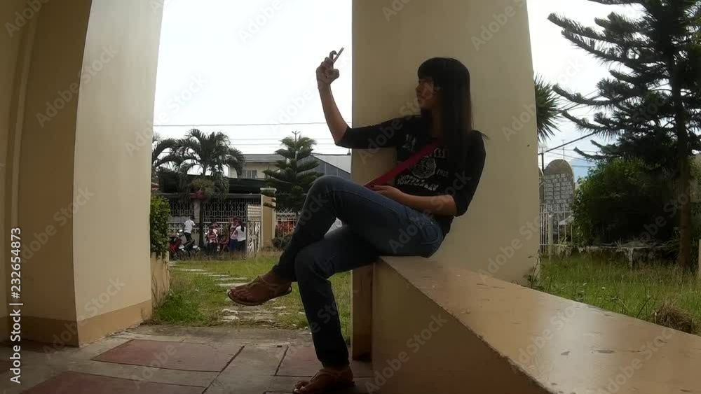 Young lady spends lots of her time taking selfie with her smartphone, becoming a vicious preoccupation of many young generation Young lady spends lots of her time taking selfie with her smartphone, becoming a vicious preoccupation of many young generation