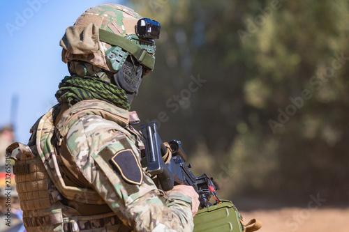 special forces, soldier assault rifle with silencer, optical sight. behind cover waiting in ambush photo