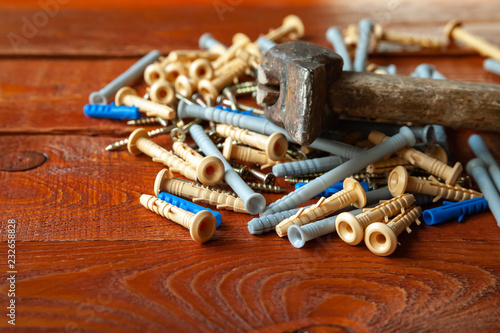 Plastic dowel screws and hammer on wooden background. Selective focus.