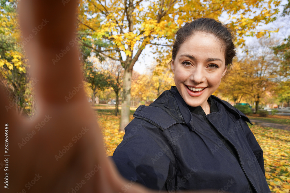 happy young woman in her 20s taking selfie photo posing in park with autumn colors - wide angle shot with invisible smartphone happy young woman in her 20s taking selfie photo posing in park with autumn colors - wide angle shot with invisible smartphone