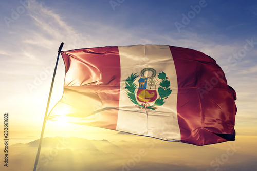 Foto Peru Peruvian flag textile cloth fabric waving on the top sunrise mist fog