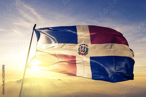 Dominican Republic flag textile cloth fabric waving on the top sunrise mist fog photo