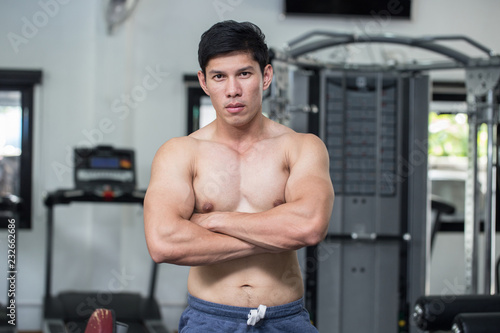 Strong Athletic Asian Man standing with crossed arms and looking at camera on gym,Muscular guy feeling so strong and healthy,Bodybuilder Concept