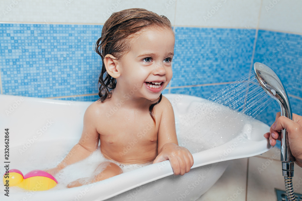 Beautiful little girl taking a bath at home. A cute baby is sitting in