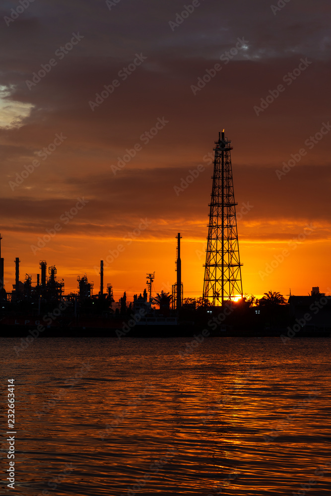 Silhouette of Oil refinery industry plant near the river before sunrise.