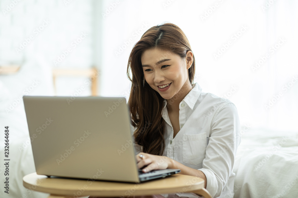 Lifestyle of Beautiful Attractive Asian woman smile working or shopping online with computer laptop in bedroom feeling so happiness and cheerful,Relax in holiday with laptop and using social network Lifestyle of Beautiful Attractive Asian woman smile working or shopping online with computer laptop in bedroom feeling so happiness and cheerful,Relax in holiday with laptop and using social network