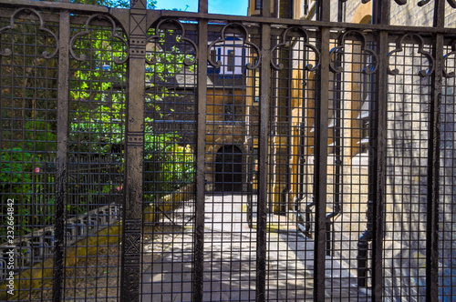 A metal grid fence covering the entrance to the old English courtyard