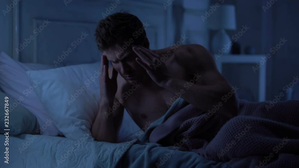 Young man suffering migraine, rubbing his temples, having bad sleep, stress Young man suffering migraine, rubbing his temples, having bad sleep, stress