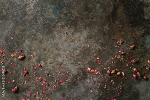 Old dark metal background with dry pink rose buds and petals. Copy space.