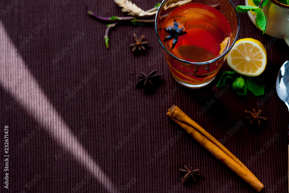 Oriental tea on a brown cloth Mat with spices and lemon. Lemon, mint, ginger, cinnamon.