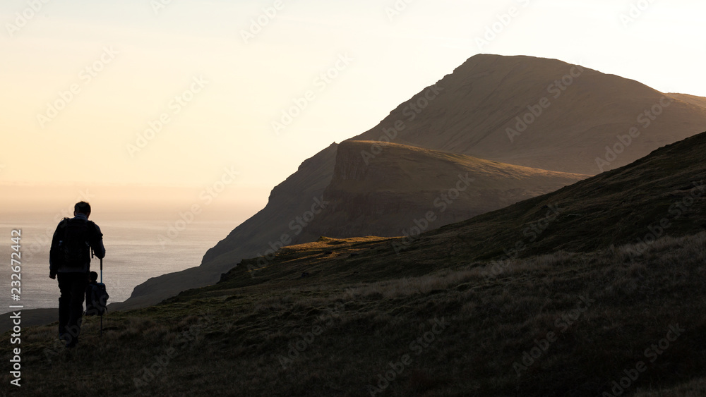 Man exploring the highlands in Faroe Islands at sunset