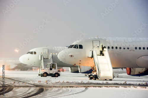 Modern twin-engine passenger airplane on the apron of airport during snow blizzard