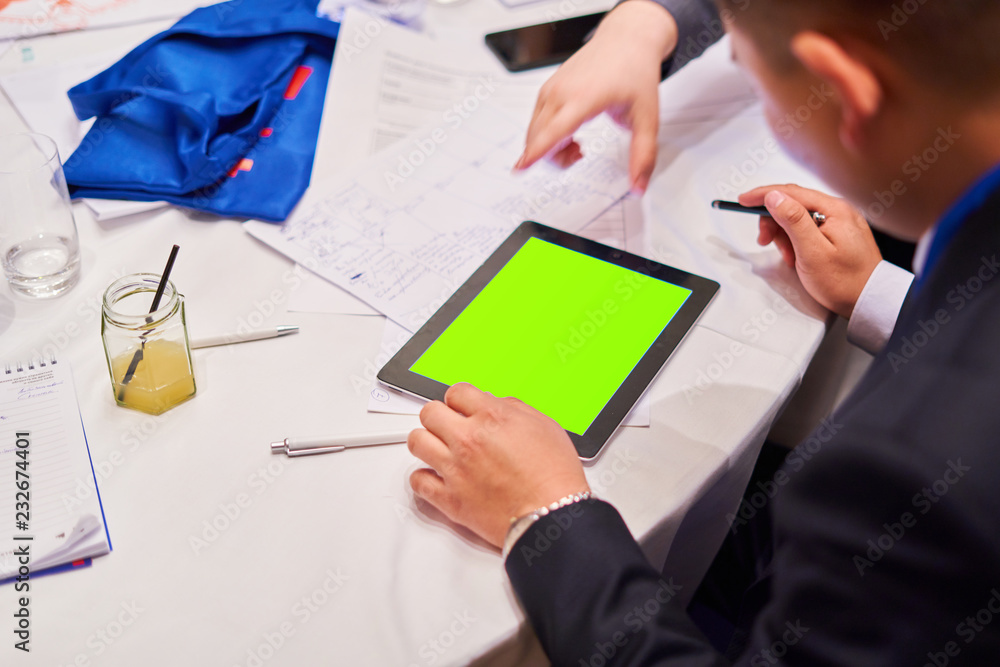 Blurred background, people sitting at the white round table - in the middle of the table is a tablet Blurred background, people sitting at the white round table - in the middle of the table is a tablet