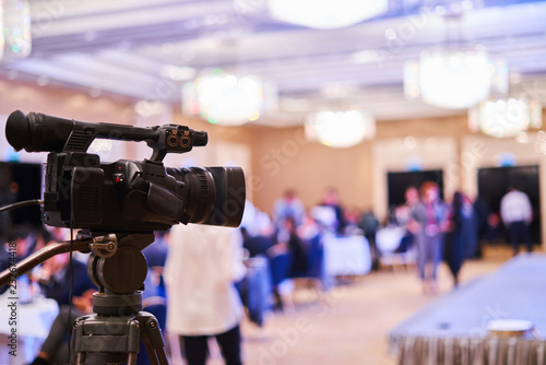 video camera stands on a tripod - video of the conference, blurred background