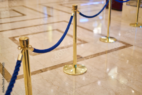 golden fence with a blue rope - marble floor, background