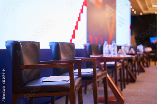 chairs and tables stand on the stage - there are papers on the chairs, the scene is blurred background