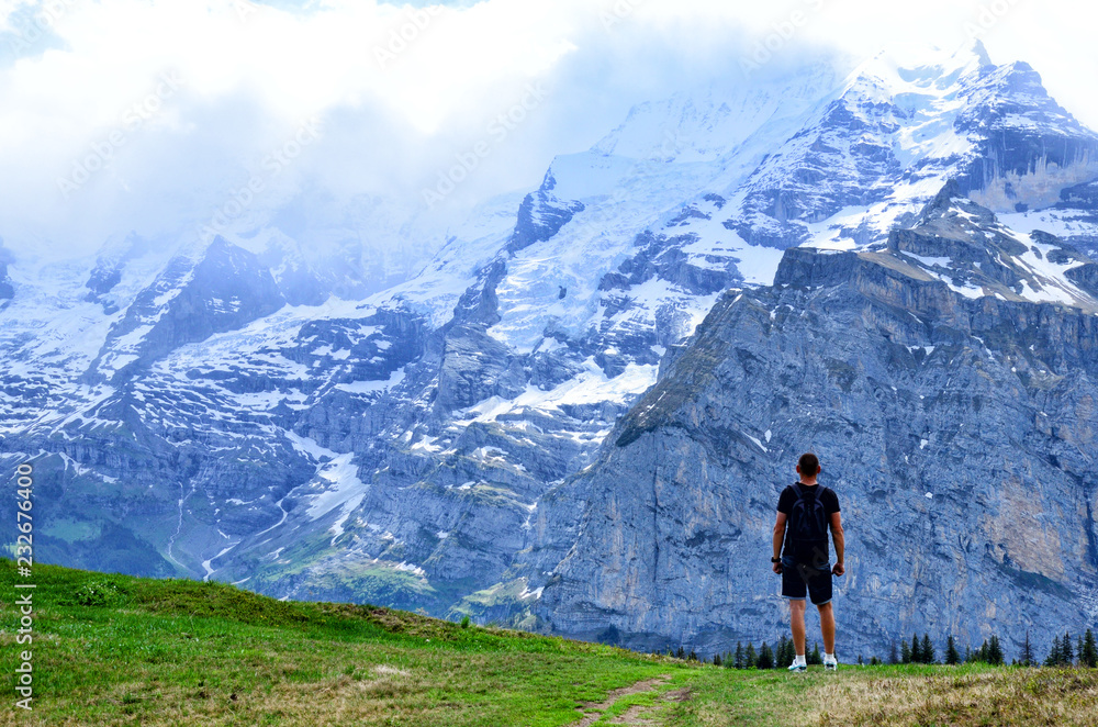 A journey man standing on a rock and look at mountains Jungfraujoch