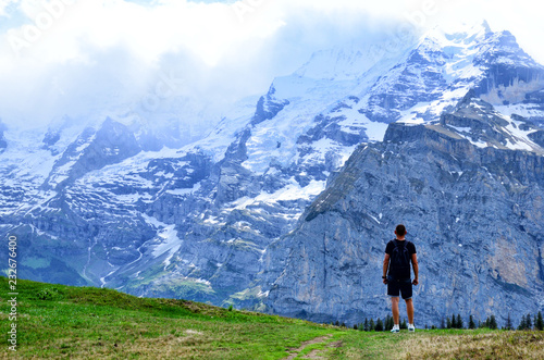 A journey man standing on a rock and look at mountains Jungfraujoch