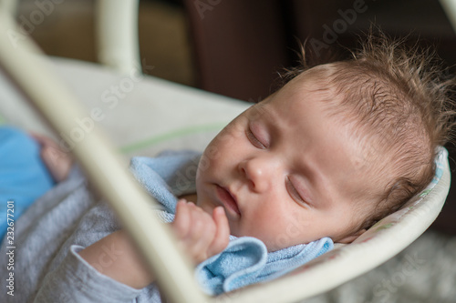 Cute newborn baby boy, sleeping in a swing