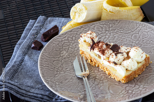 Piece of Banoffee pie with banana, chocolate, caramel and whipped cream. Selective focus. photo