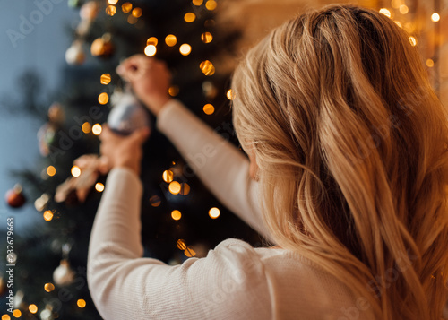 girl with blond hair hangs a toy on the tree