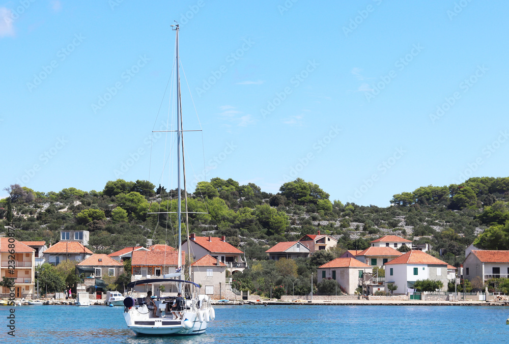 Kaprije, Croatia, Europe - 7 9 2018: Embankment of a small Croatian town in the Adriatic Sea. Sailing yacht on the background of the Dalmatian Riviera. Tourism and architecture of the Mediterranean. 