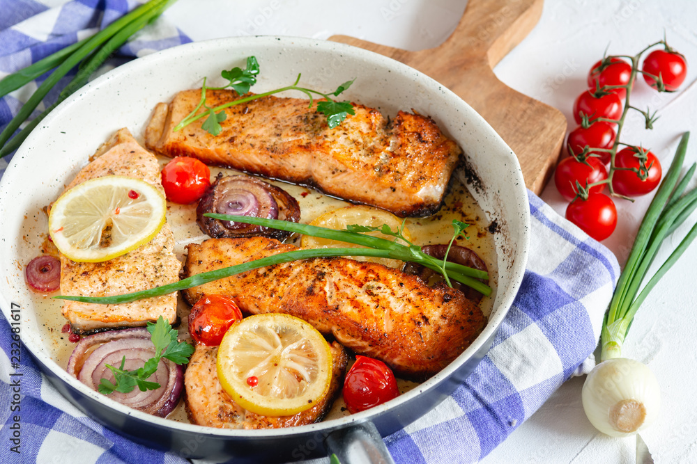 Salmon fried in a pan with onions, lemon and cherry tomatoes Salmon fried in a pan with onions, lemon and cherry tomatoes