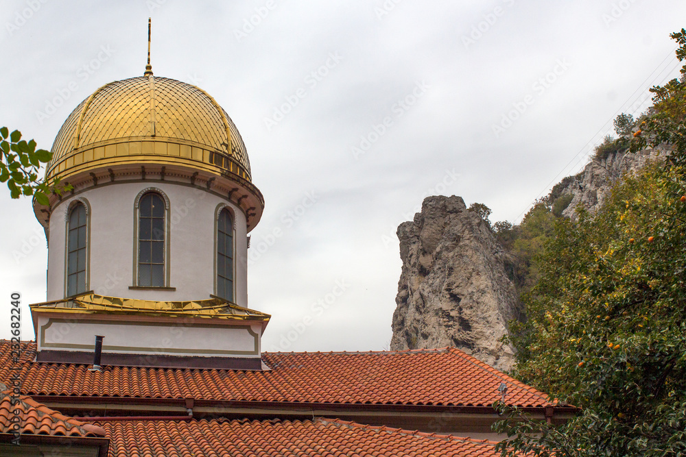 The Golden Dome of the Orthodox Church of the Virgin Mary, better known as the Fish Church, against the background of the sky and mountain rocks. Asenovgrad, Bulgaria.