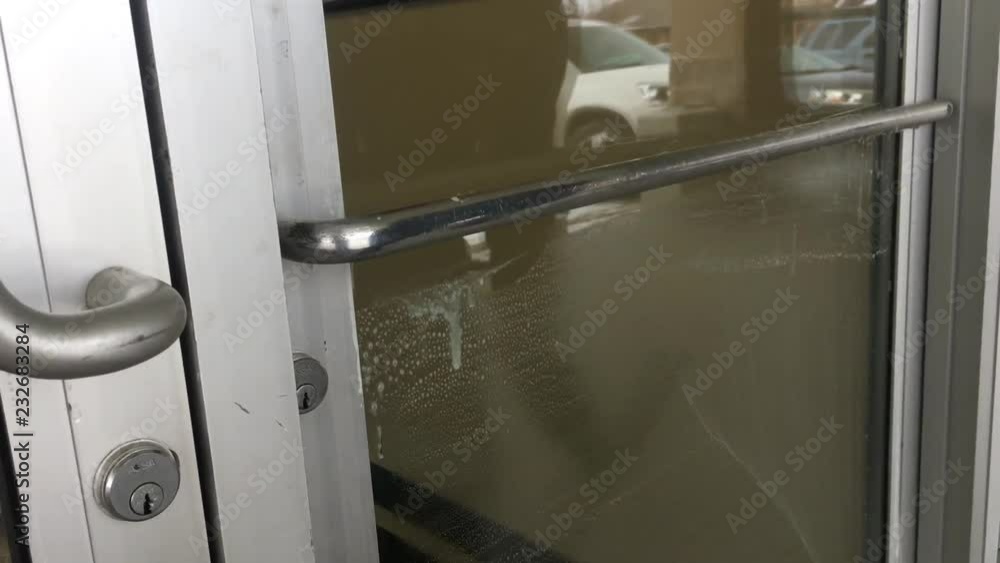 Window washing worker cleans glass with soapy water before using rubber edge squeegee to remove water thereafter. Window washing worker cleans glass with soapy water before using rubber edge squeegee to remove water thereafter.