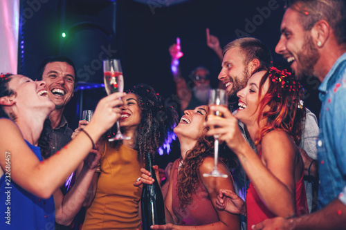 Group of friends dancing and drinking champagne at nightclub party - Happy young people having fun celebrating together in disco club - Entertainment, nightlife and youth lifestyle