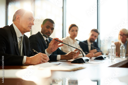 Obraz na plátně Senior politician in formalwear speaking in microphone at international conferen