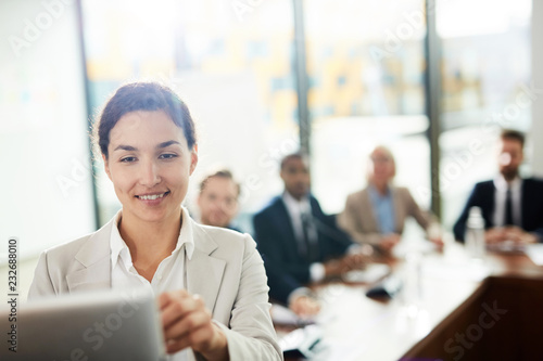 Young smiling speaker looking at whiteboard while preparing her report or presentation