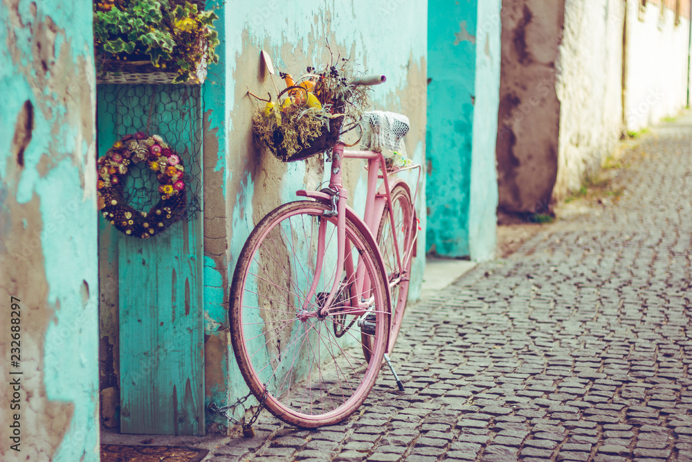 Pink vintage bike with basket full of flowers next to an old cyan building  in Spain Stock Photo | Adobe Stock