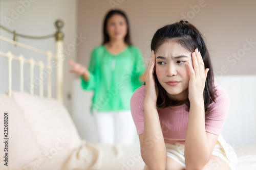 Troubled teenage girl was bored while her mother is scolding in the background.Problems between generations concept.