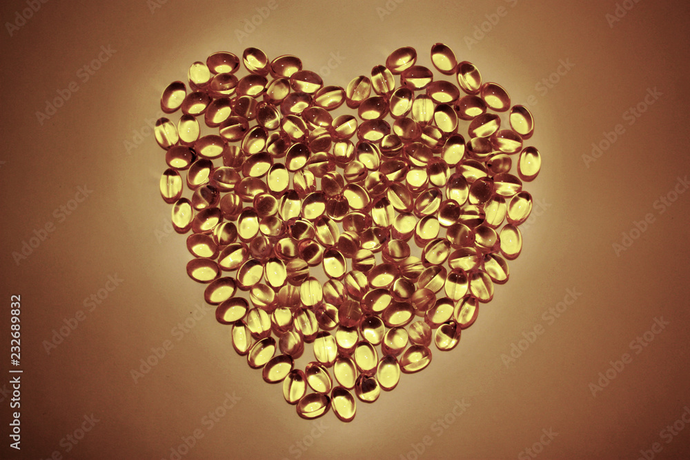 Gel pills lying in the shape of a heart on white background. Yellow capsules omega 3. Concept of careful attitude to the health. Healthy lifestyle, biologically active additive, dietary nutritional. Gel pills lying in the shape of a heart on white background. Yellow capsules omega 3. Concept of careful attitude to the health. Healthy lifestyle, biologically active additive, dietary nutritional.