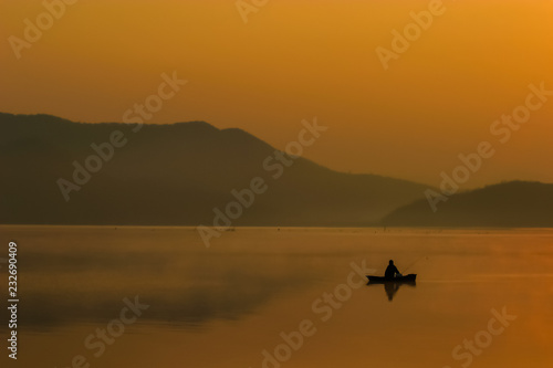 Silhouette Fishing man sitting on his boat with sunset sky and seclective focus, Background for travel or relax, Thailand