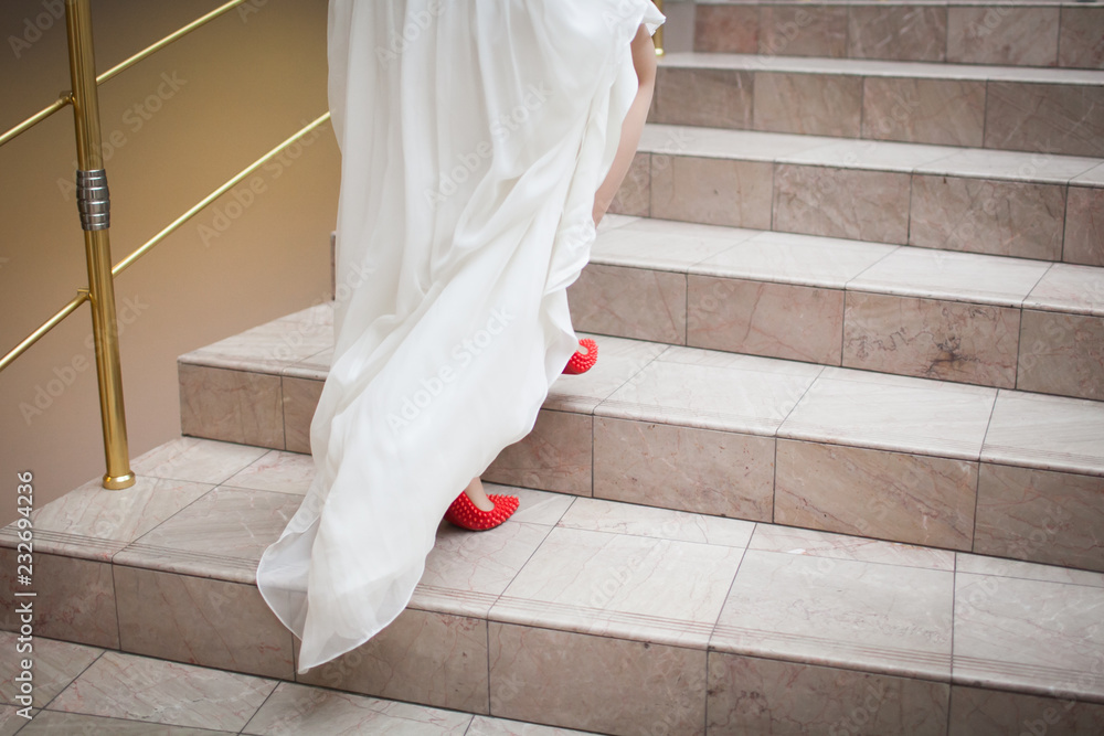 The legs of the bride in bright shoes climb the stairs to the registry office The legs of the bride in bright shoes climb the stairs to the registry office
